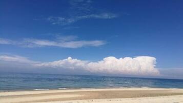 A beach with a clear sky and a large cloud formation.
