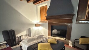 Une chambre à coucher avec un lit, une cheminée, un téléviseur et un canapé rouge.