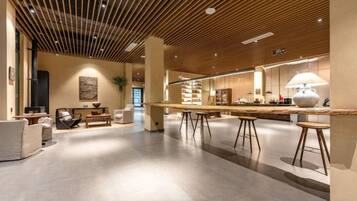 A spacious, modern interior with a wooden ceiling, a long dining table, and comfortable seating areas.