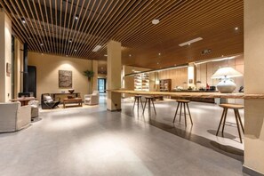 A spacious, modern interior with a wooden ceiling, a long dining table, and comfortable seating areas. - Man buGarden Hotel (Ningbo)