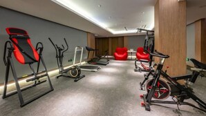 A gym with exercise equipment including treadmills, stationary bikes, and a rowing machine. - Man buGarden Hotel (Ningbo)