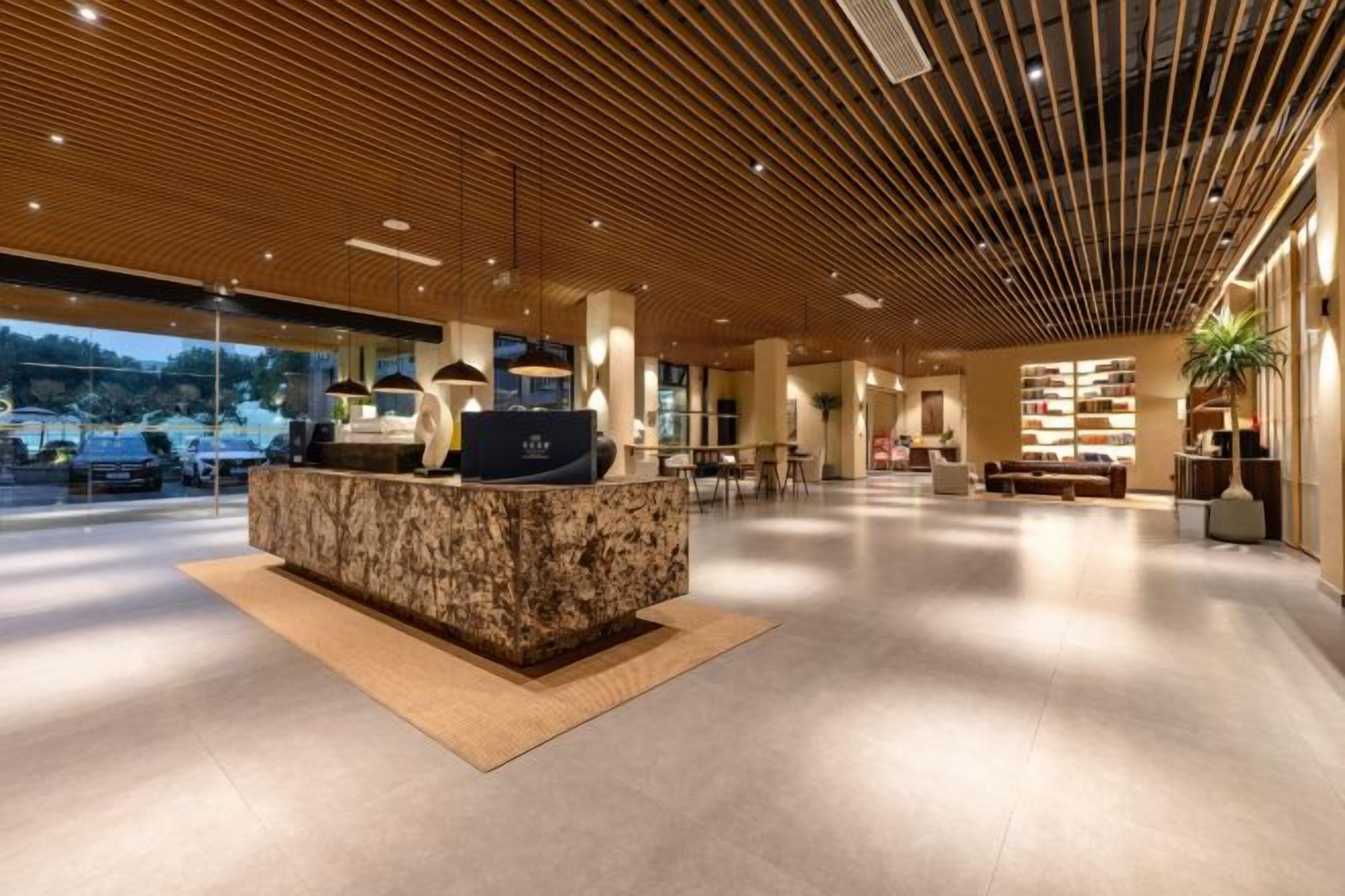 A modern reception area with a marble counter, wooden ceiling, and a view of the outdoors.