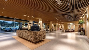 A modern reception area with a marble counter, wooden ceiling, and a view of the outdoors. - Man buGarden Hotel (Ningbo)