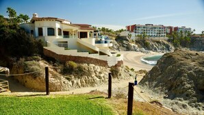 Ein Küstenhotel mit einem großen Balkon mit Blick auf den Strand, einer Treppe zu den oberen Stockwerken und einem Schild, das darauf hinweist, dass Tierkot unerwünscht ist.