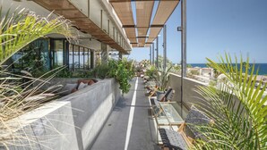 Ein Balkon mit Sitzgelegenheit im Freien, Blick auf das Meer und Kübelpflanzen.