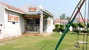 A gift shop with a sign, a swing set, and a well-maintained lawn. - Ethnic India Tourist Resort (Sonepat)