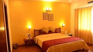 A hotel room with a large bed, a nightstand, a wall-mounted lamp, and a picture frame. - Ethnic India Tourist Resort (Sonepat)