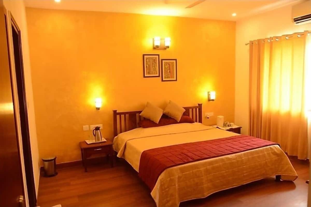 A hotel room with a large bed, a nightstand, a wall-mounted lamp, and a picture frame.