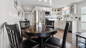 A modern kitchen with white cabinets, a central island, and pendant lighting. - 1214 Lambeau Field Luxe (Green Bay)