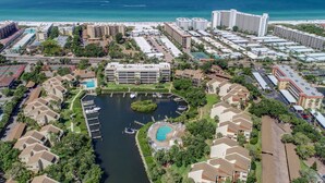 An aerial view of a coastal resort with a marina, swimming pool, and beachfront hotels. - Midnight Cove II Bldg 6, 2nd Fl Near Pool (Siesta Key)