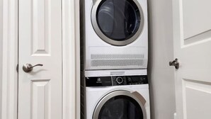 A laundry room with two stacked front-loading washing machines. - The Cozy Cove Modern King-Bedroom Full Apartment (St. Catharines)