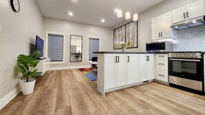 A modern kitchen with white cabinets, a stainless steel oven, and pendant lighting. - The Zen Escape Modern Queen-Bed Full Apartment (St. Catharines)