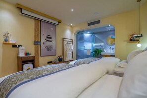 Ein Hotelzimmer mit einem großen Bett, einem kleinen Schreibtisch, einem Spiegel und einer Dusche.