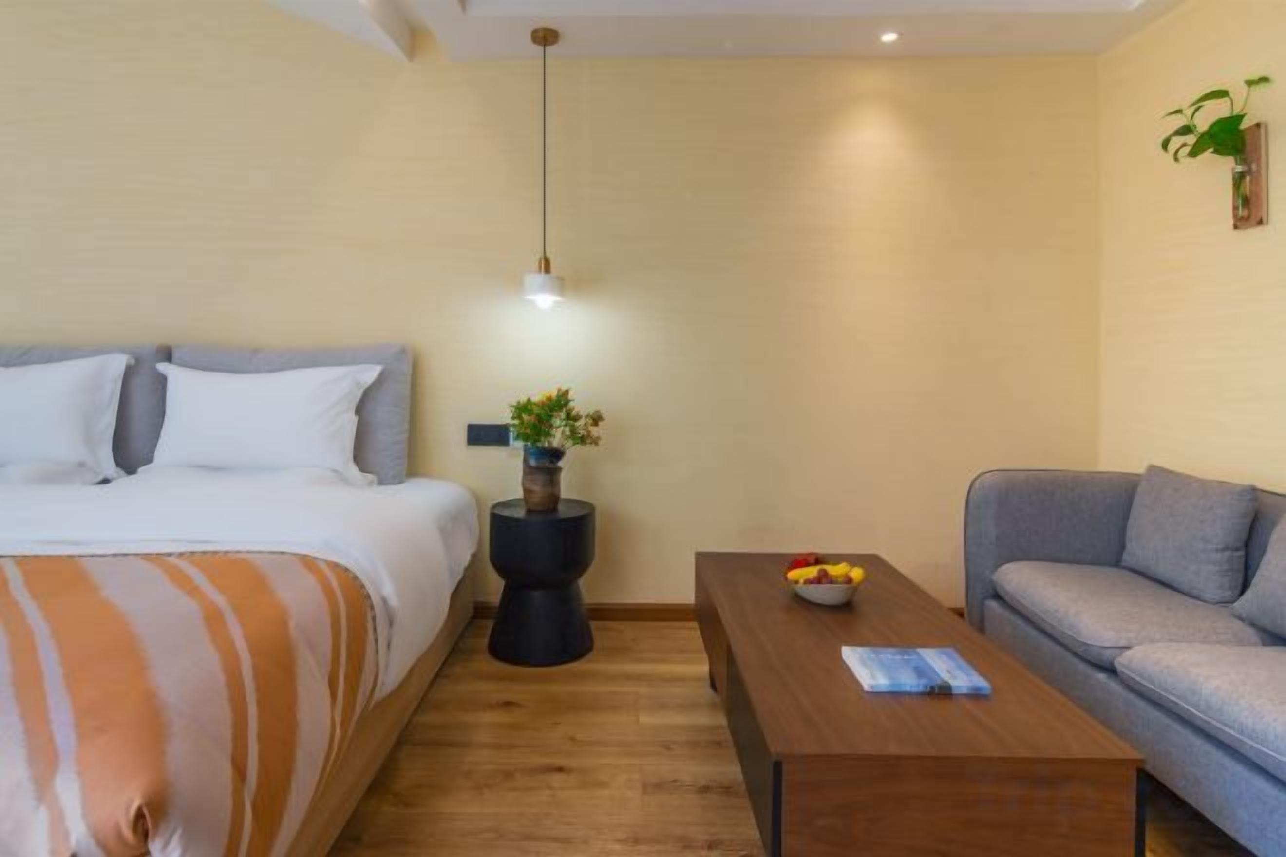A bedroom with a bed, bedside table, and a small table with fruits.