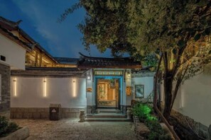 A traditional courtyard with a wooden gate, stone steps, and a tree. - Lijiang Shechen Inn (Lijiang)