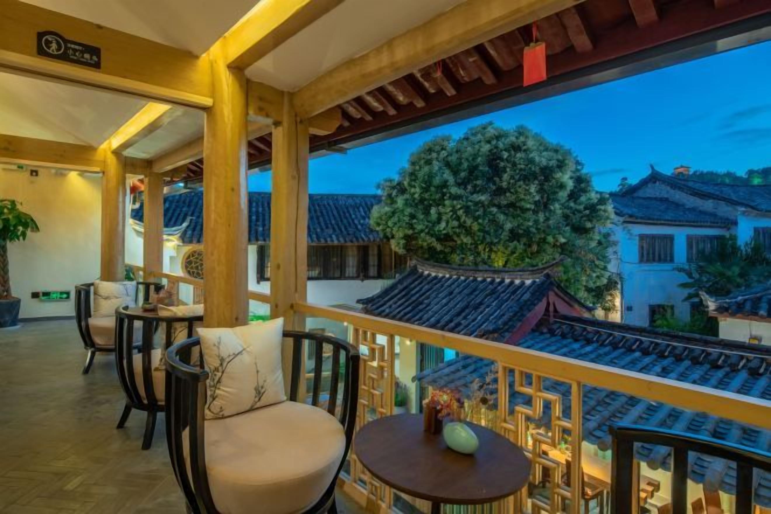 Varanda em estilo tradicional, com grades de madeira, vista para edifícios típicos e uma mesa com um vaso.