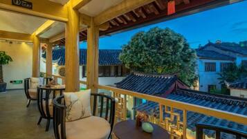 Varanda em estilo tradicional, com grades de madeira, vista para edifícios típicos e uma mesa com um vaso.