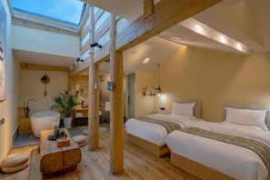 Una camera da letto con lucernario, travi in legno, un letto grande, comodini e un bagno con vasca.