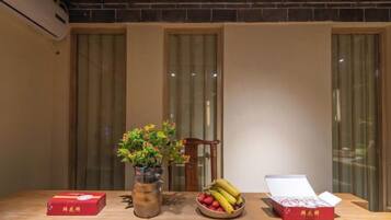 Uma mesa de madeira com um vaso de flores, uma tigela de frutas e duas caixas abertas que parecem conter alimentos embalados.