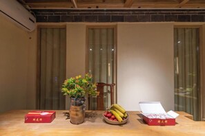 A wooden table with a vase of flowers, a bowl of fruit, and two open boxes of what appears to be a packaged food item. - Lijiang Shechen Inn (Lijiang)