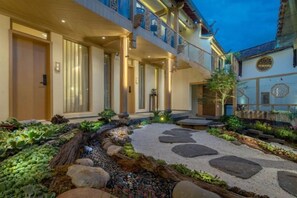 A hotel with a covered outdoor area, a stone pathway, and a small water feature. - Lijiang Shechen Inn (Lijiang)