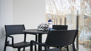 A balcony with a round table and two chairs, a helmet, and a water bottle. - STANDARD DOUBLE  BED APARTMENT  (Banyoles)