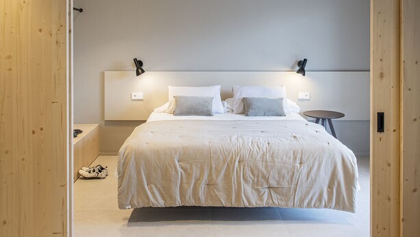 A modern bedroom with a large bed, wooden paneling, and recessed ceiling lights. - STANDARD DOUBLE  BED APARTMENT  (Banyoles)