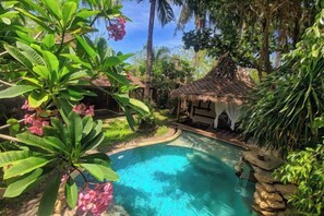 A pool surrounded by lush greenery and a thatched-roof structure. - Villa with Private Swimming Pool Gili Trawangan (Gili Trawangan)