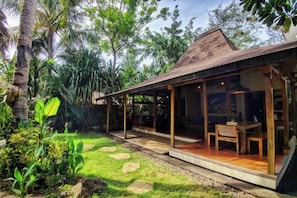 A modern house with a glass-enclosed porch, a dining area, and a garden with tropical plants. - Villa with Private Swimming Pool Gili Trawangan (Gili Trawangan)