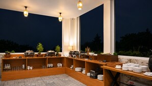 A buffet setup with various food stations, a grill, and a seating area with a view of the outdoors. - Aotel by Clarks Inn Palampur (Palampur)