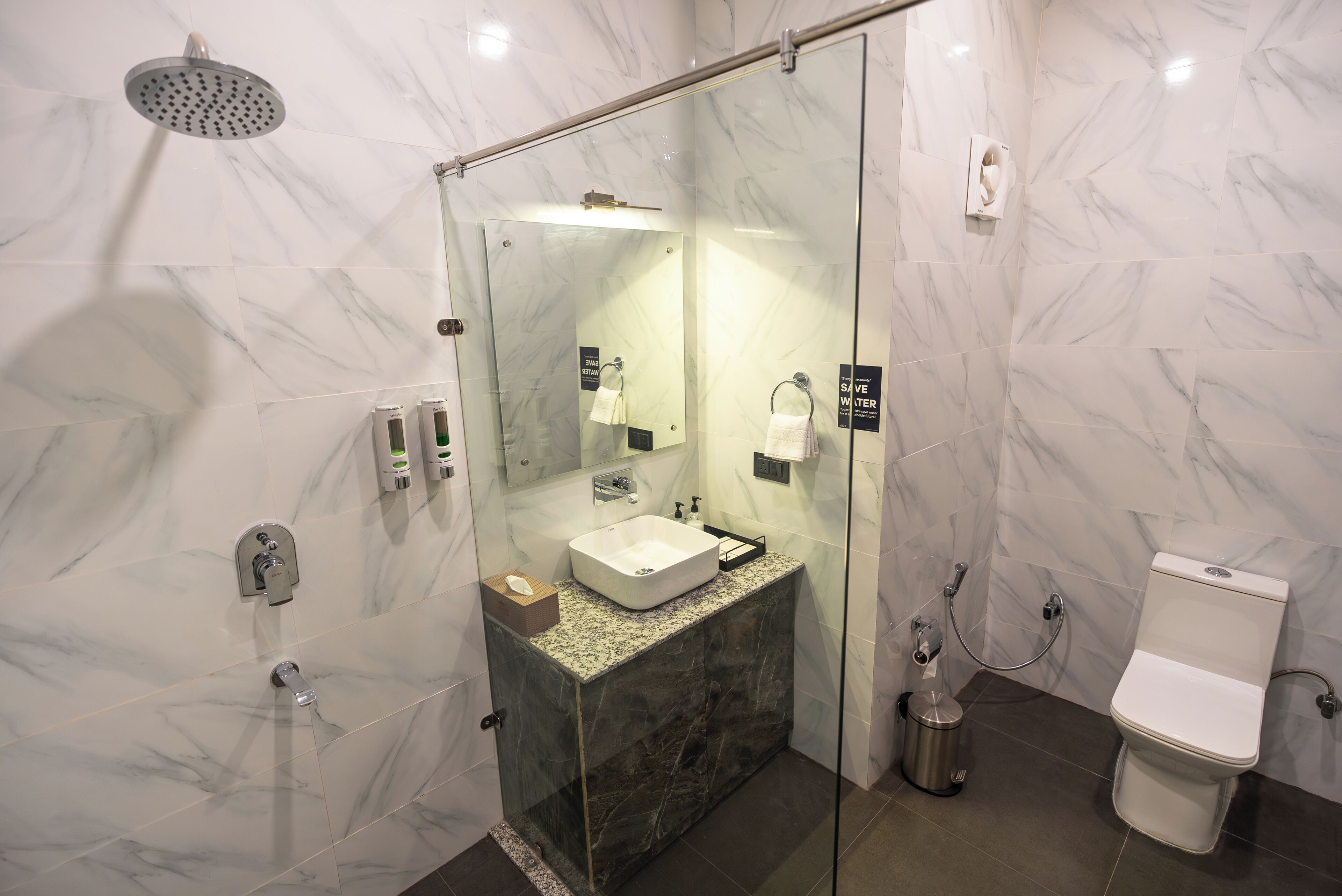 A modern bathroom with a glass-enclosed shower, a marble sink, and a toilet.