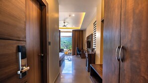 A modern hotel hallway with wooden doors, a flat-screen TV, a ceiling fan, and a view of a green landscape. - Aotel by Clarks Inn Palampur (Palampur)