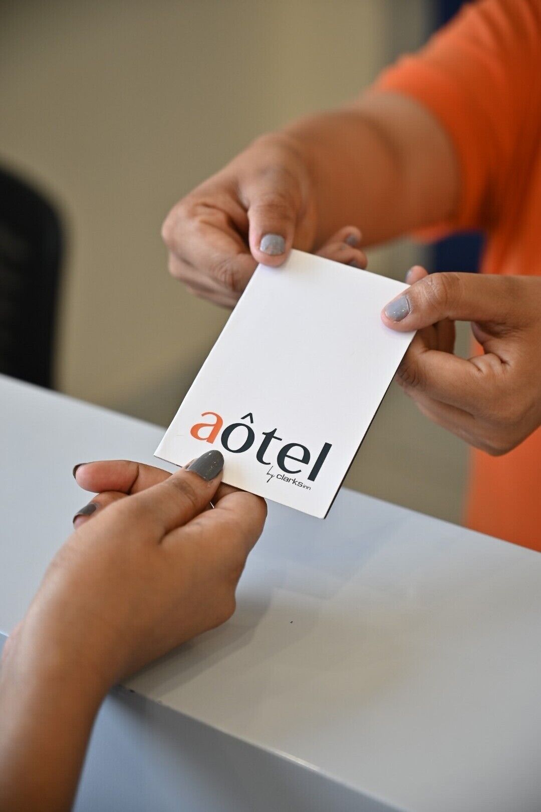 Una persona sostiene una tarjeta blanca con el texto 'aotel' y 'Clarksnn', probablemente el nombre de un hotel o marca.