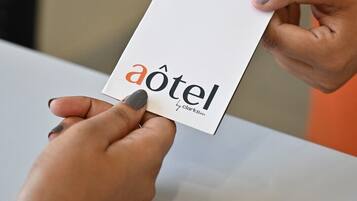 Una persona sostiene una tarjeta blanca con el texto 'aotel' y 'Clarksnn', probablemente el nombre de un hotel o marca.