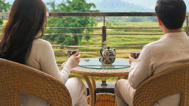 Two people seated at a round table with a teapot, overlooking a scenic view of mountains and greenery. - Aotel by Clarks Inn Palampur (Palampur)