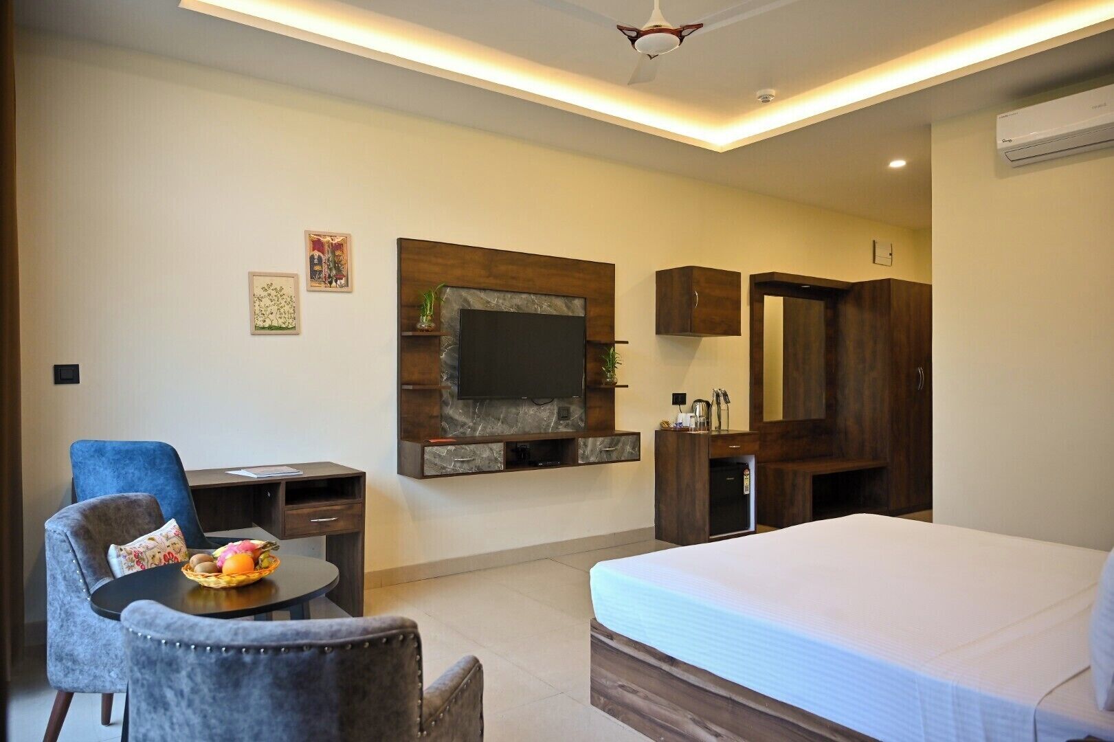 Een hotelkamer met een bed, bureau, stoel, televisie aan de muur en een kledingkast.