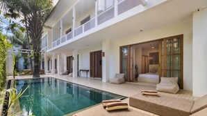 A poolside area with a pool, lounge chairs, and a covered seating area. - White Goose Boutique Hotel (Bali)