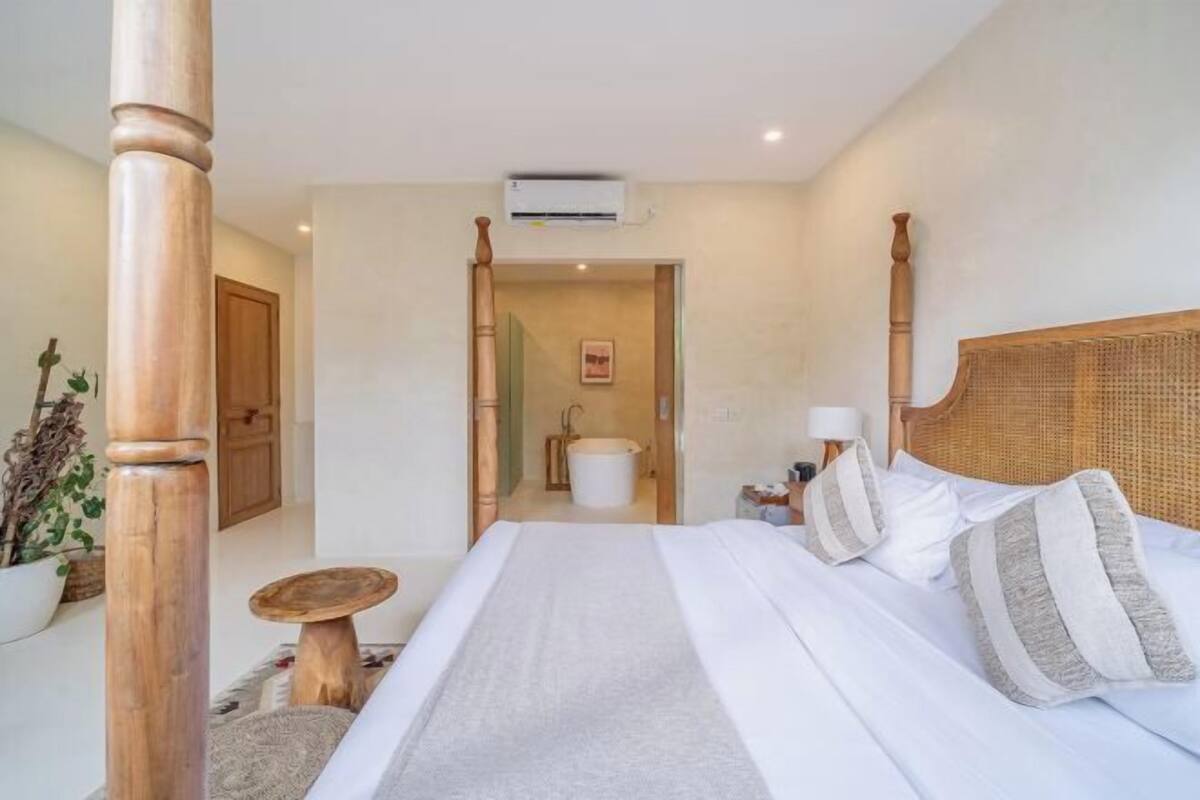 A bedroom with a bed, bedside table, and a view into the bathroom.