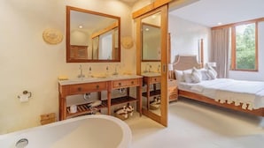 A modern bathroom with a freestanding bathtub, wooden vanity, and a large mirror. - White Goose Boutique Hotel (Bali)