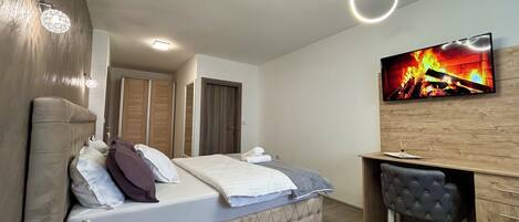 Un dormitorio moderno con cama, mesitas de noche, un escritorio y televisión.