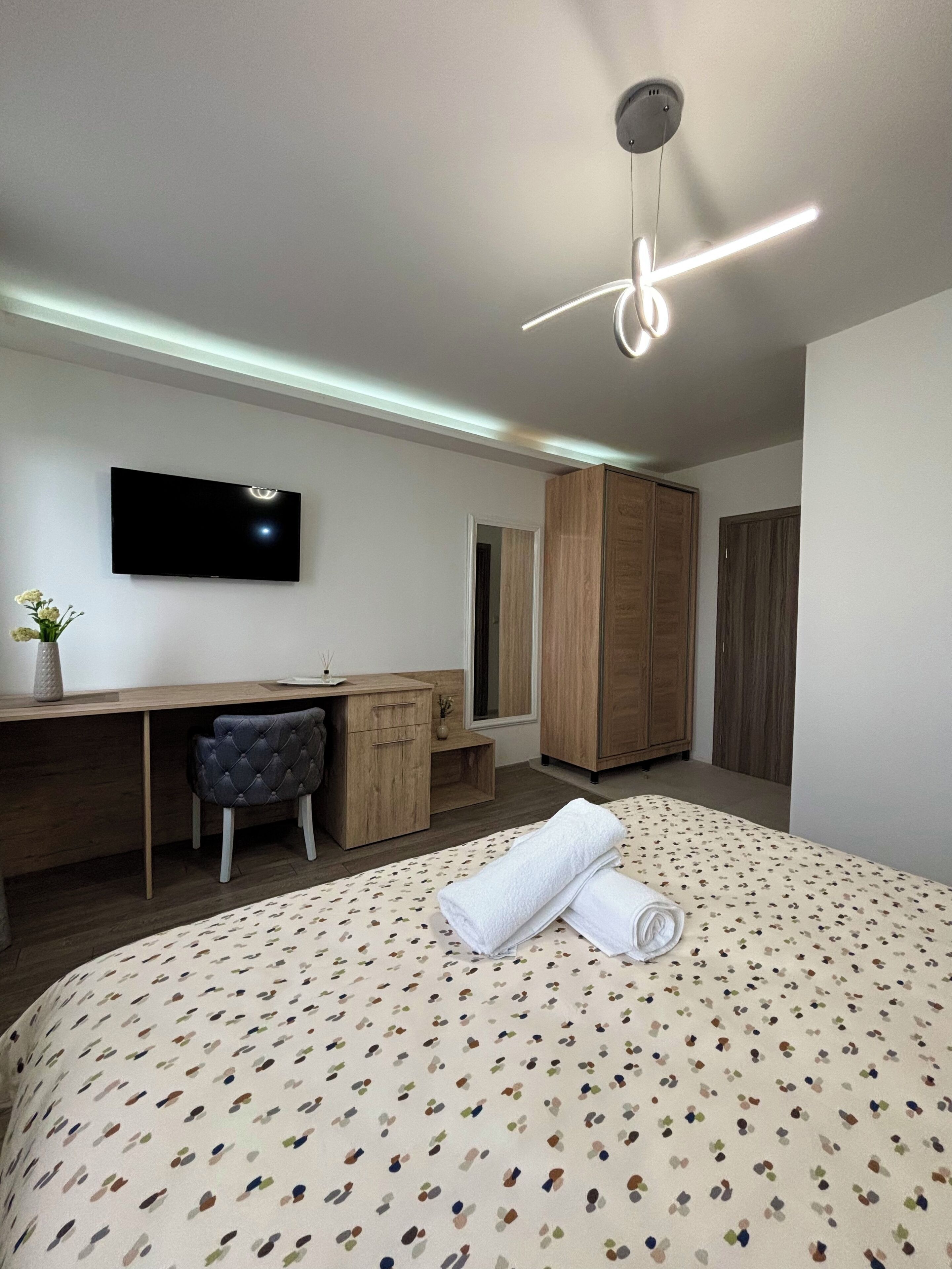 Una habitación de hotel moderna con cama, escritorio, silla, armario y televisión.