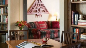 A cozy reading nook with a wooden table, a red mug, and a book. - Montford Inn & Cottages (Norman)