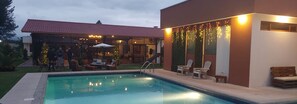 Une piscine avec des chaises longues et un espace patio couvert.