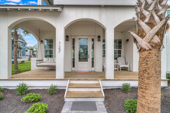A modern house with a porch, a number '127' on the wall, and a palm tree. - Luxe three-story home with a pool, gas fireplace, game room, & washer/dryer (Port Aransas)