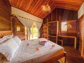 A wooden cabin with a bed, a bench, and a hanging light fixture. - Caravelas Praia (Amontada)