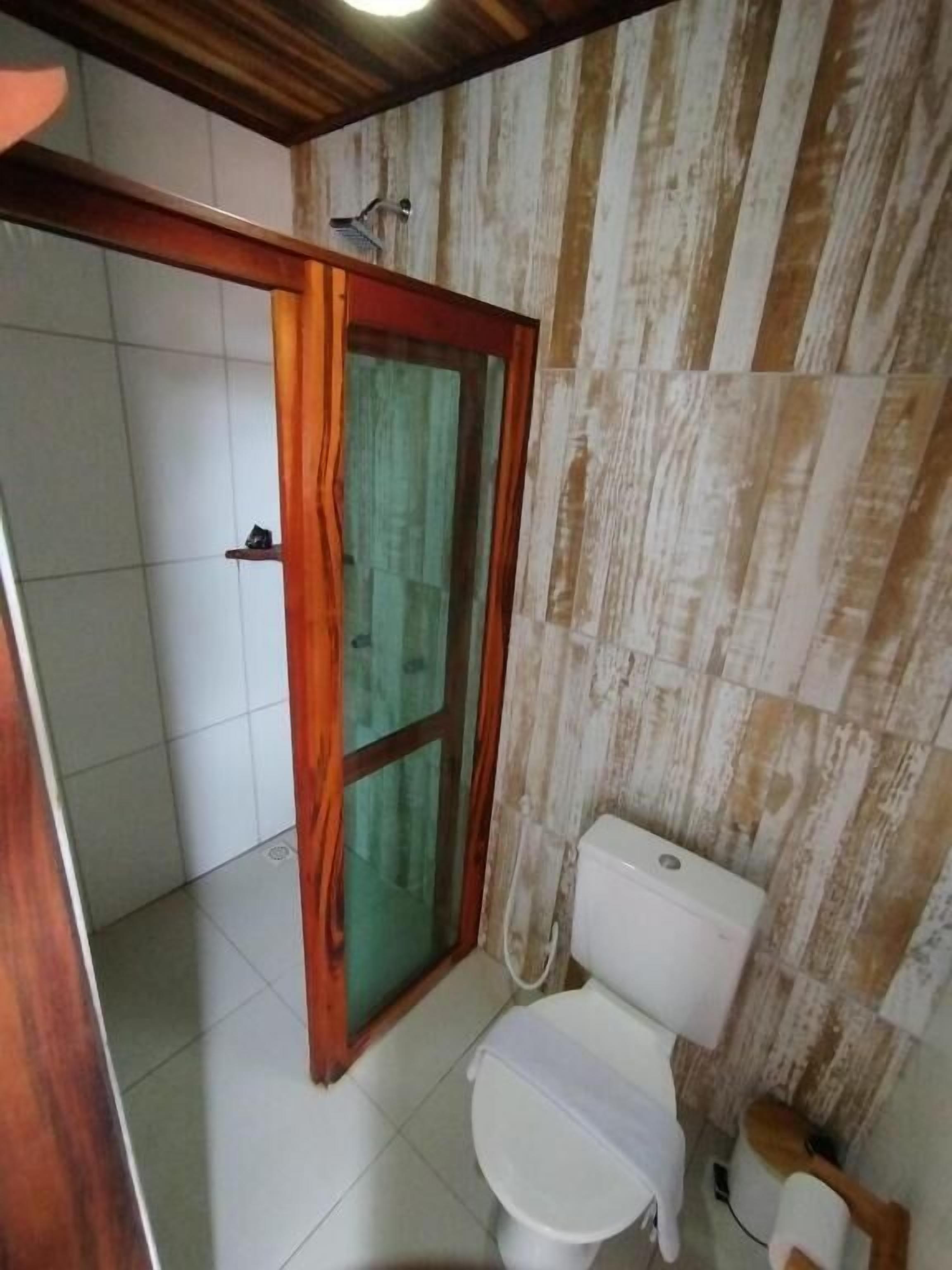 Ein Badezimmer mit Toilette, Duschbereich und Holzboden.