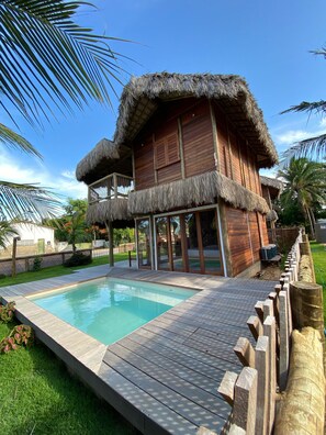 A wooden house with a thatched roof and a swimming pool. - Caravelas Praia (Amontada)