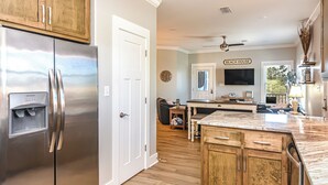 A kitchen with a stainless steel refrigerator, wooden cabinets, a marble countertop, and a ceiling fan. - 7020 Rookery 3 Someday Came Close to Beach two Pool Beach Amenities (Gulf Shores)