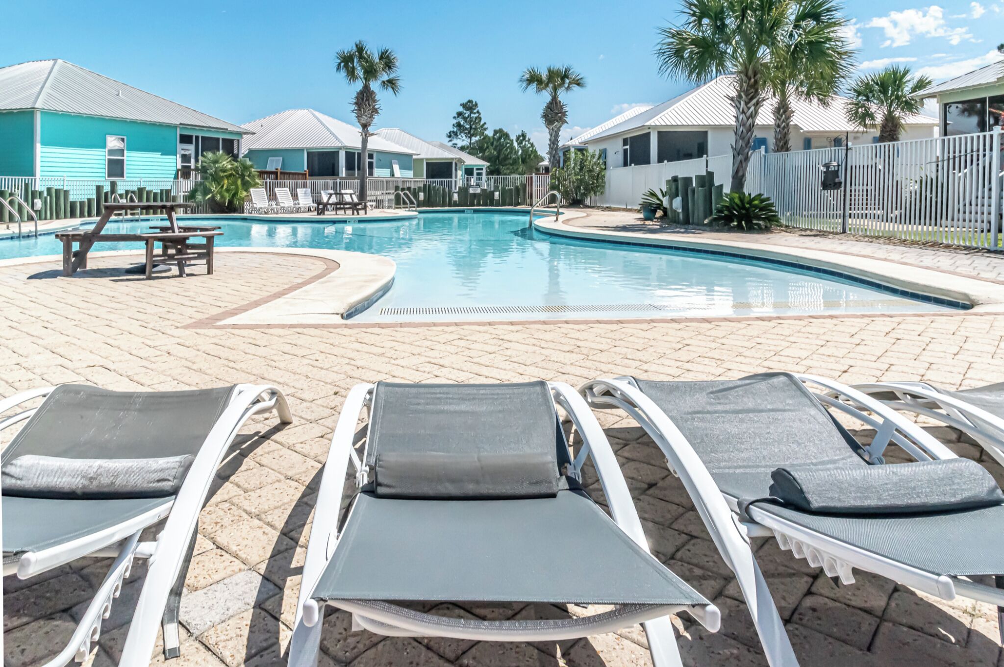 A pool area with lounge chairs and a wooden table.