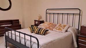 A bed with a metal frame, a bedside table with a lamp, and a wall-mounted mirror. - Casa in Centro a Giarre (Giarre)